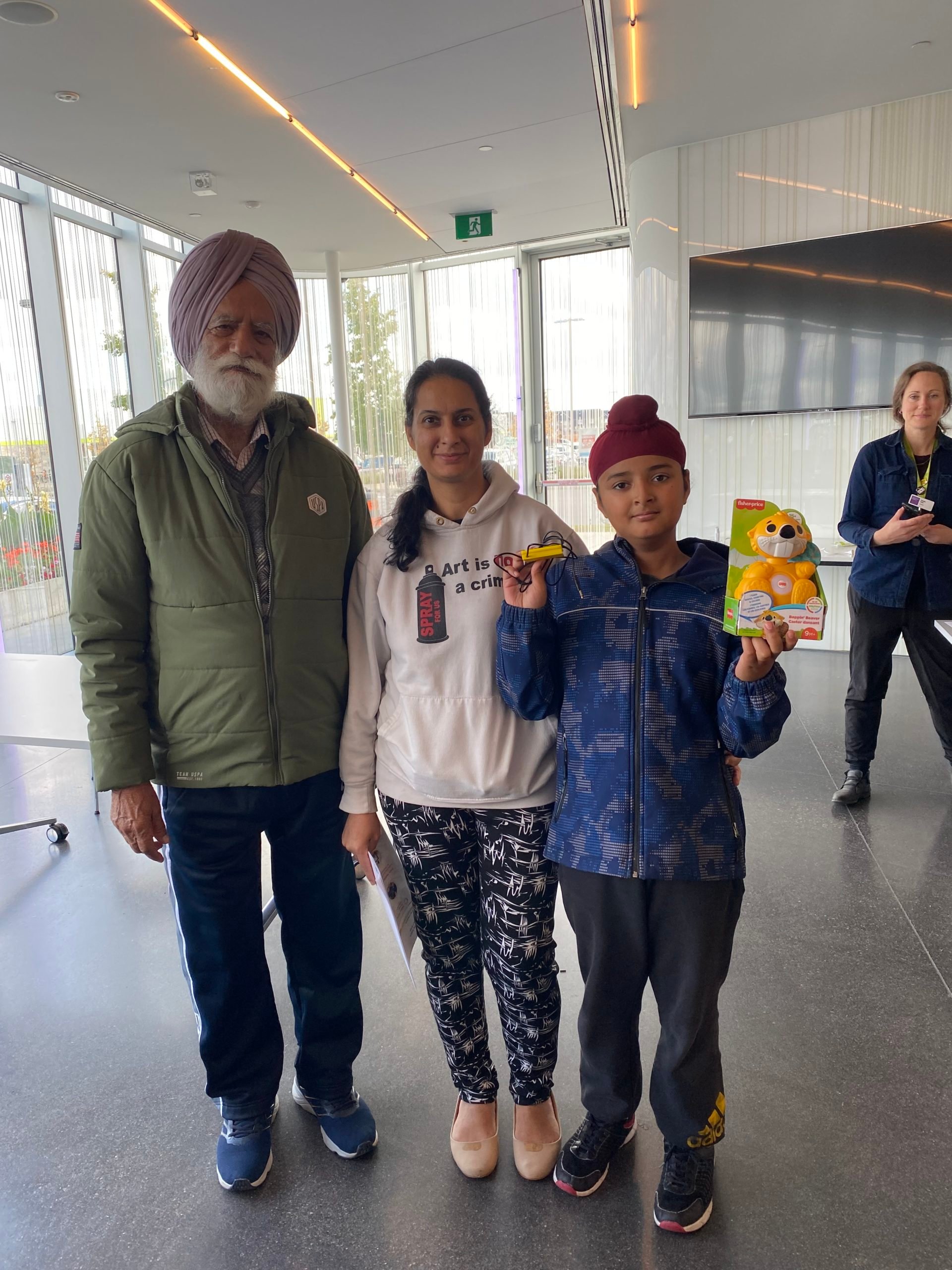 Two adults and a school aged toy holding an adapted toy beaver