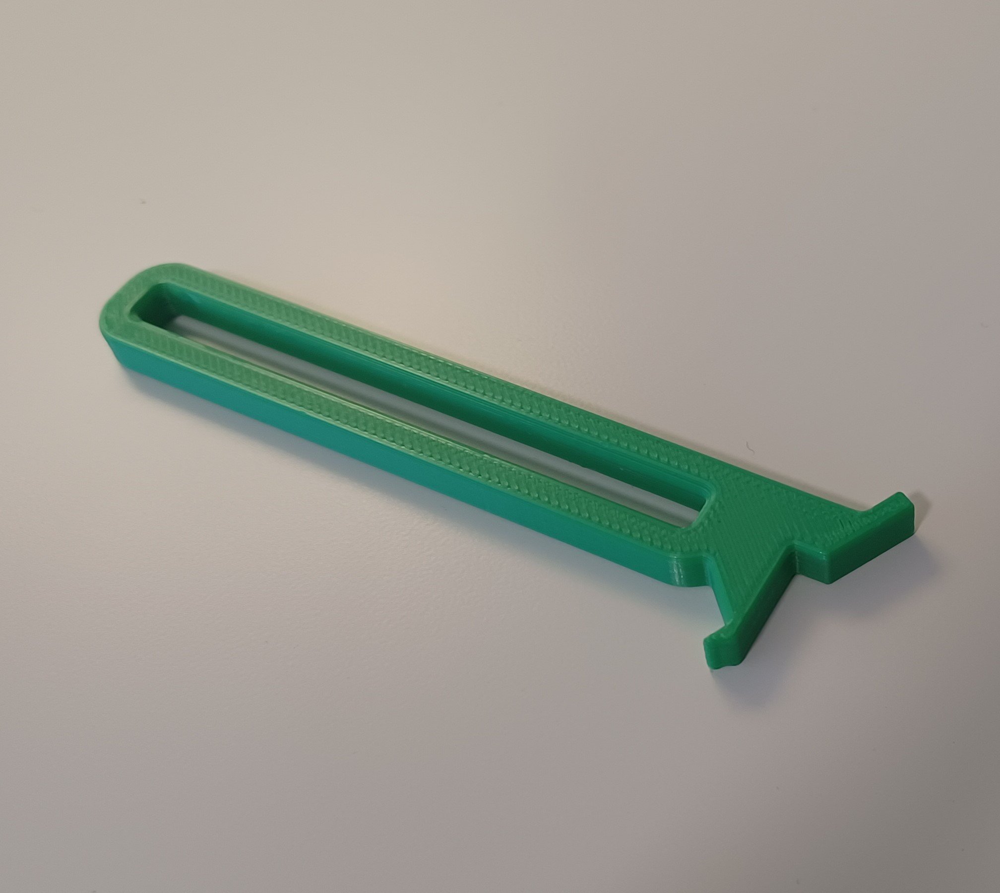 A green 3d printed beverage can opener on white background.
