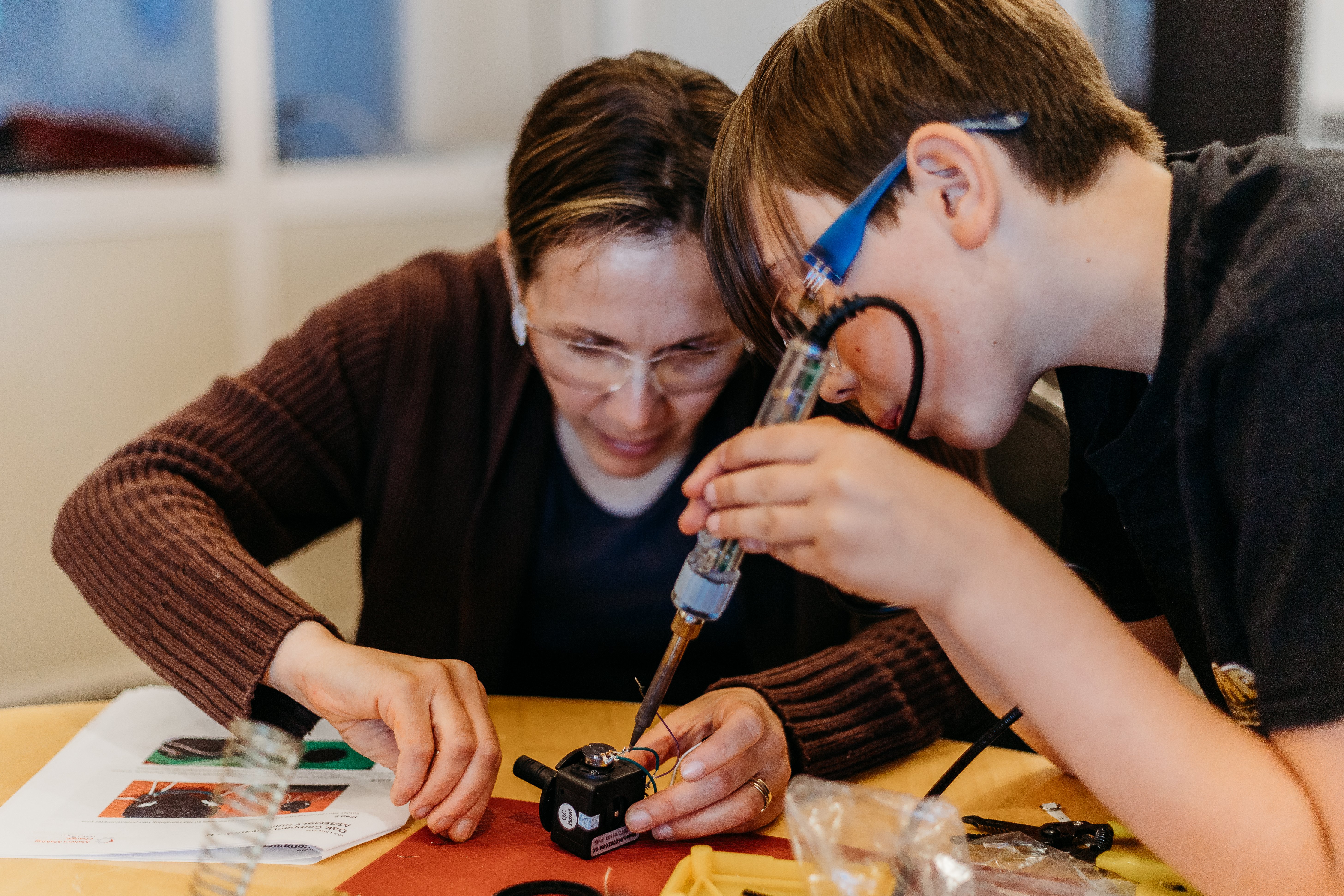 Two volunteers soldering a joystick part.