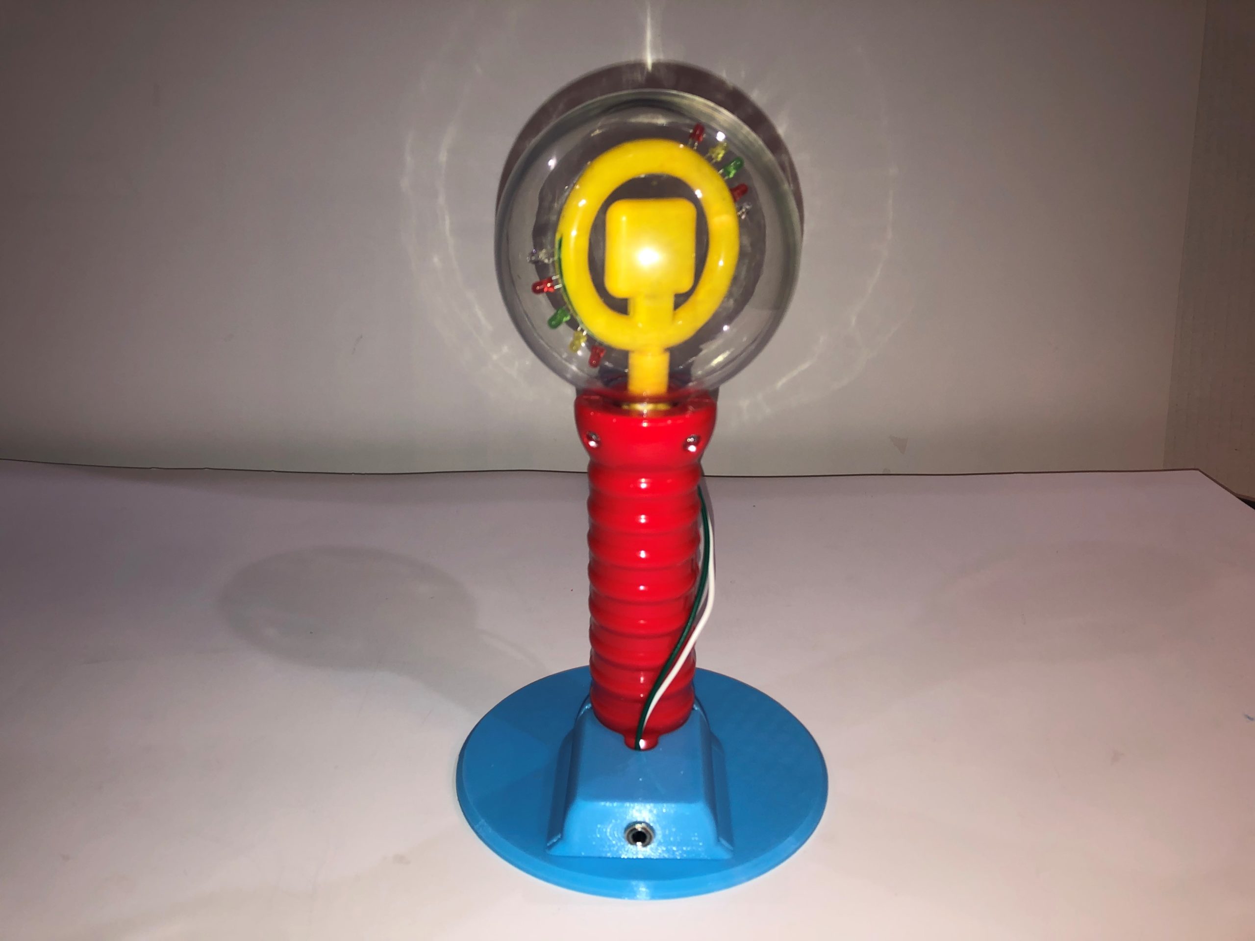 A red and yellow spinning light wand on a blue 3d printed base.