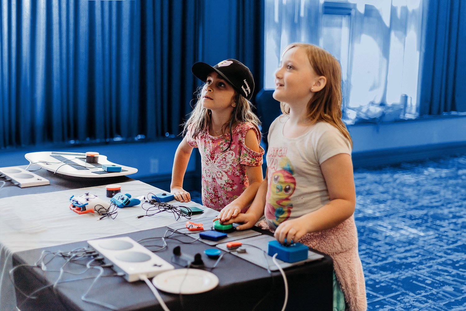 Two girls playing a video game with adaptive joysticks and switches.