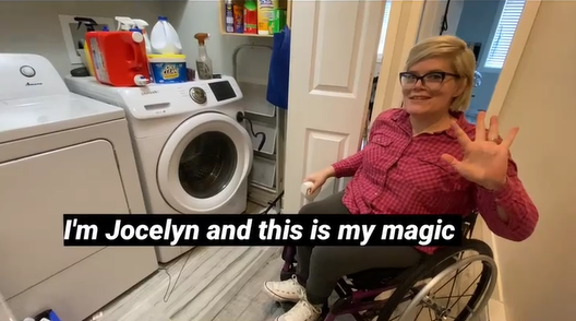 A woman in a wheelchair holding a 3d printed plunger for a laundry machine.