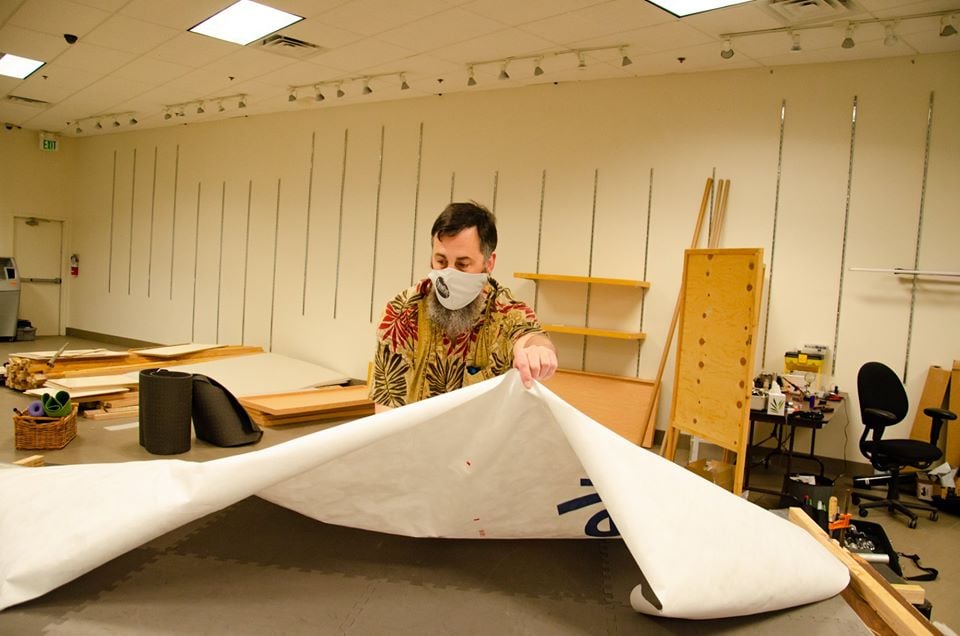 A volunteer lifting up a long piece of material.