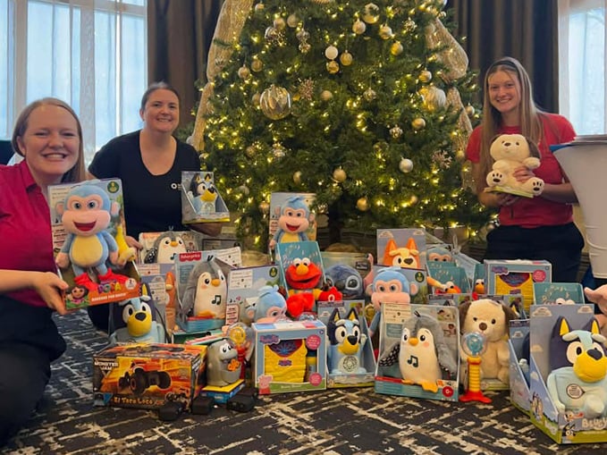 3 Neil Squire Staff posing around a pile of adapted toys and a Christmas tree