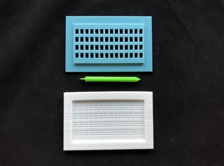 A blue and white 3d printed braille stylus set on a black cloth