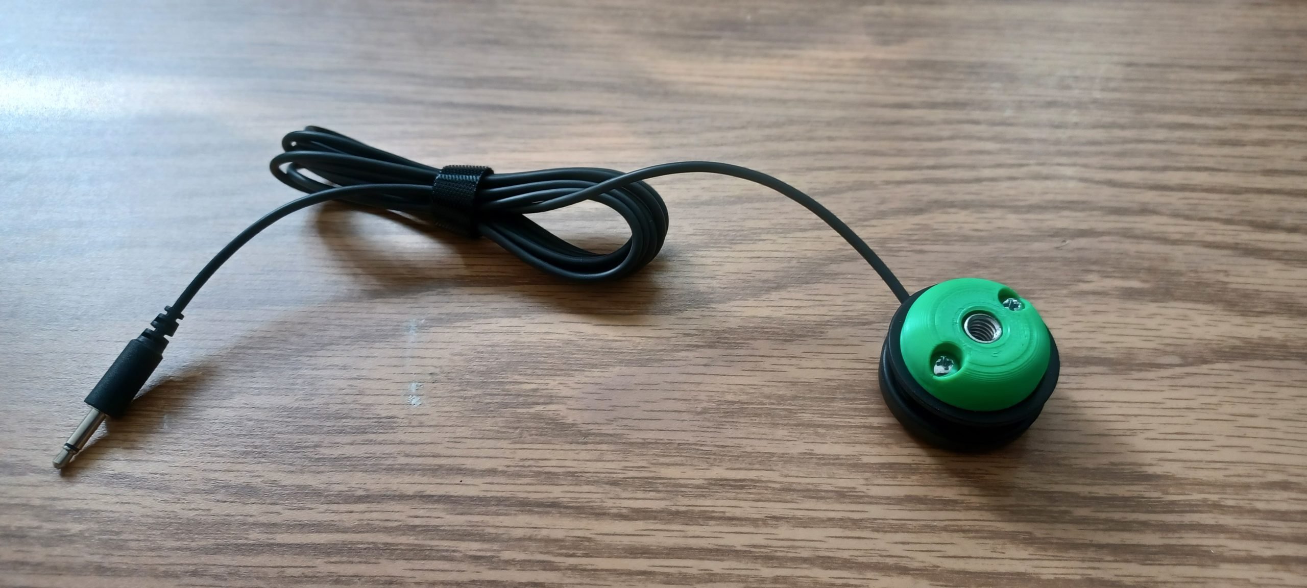 A green 3d printed adapted attached to Logitech's small button