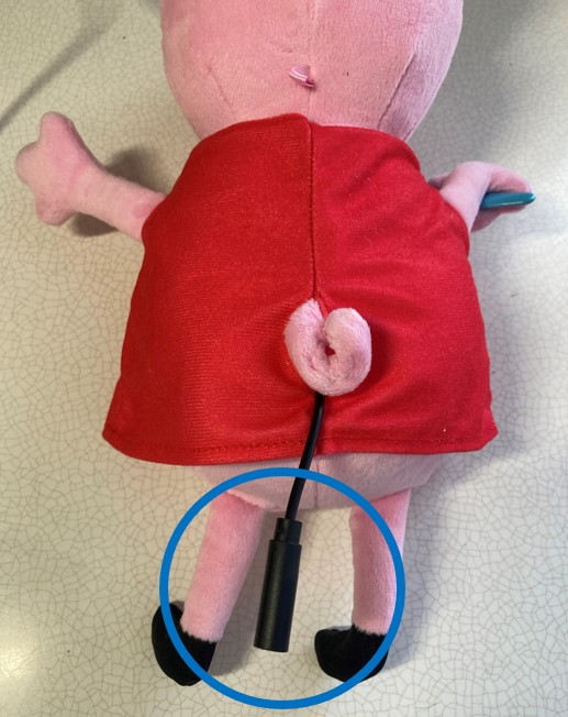 The back of a switch-adapted peppa pig toy with a blue circle highlighting a black mono cable plug.