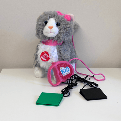 Grey and white cat plush toy with a pink bow on its right ear, a pink leash and two switches plugged into the leash handle.