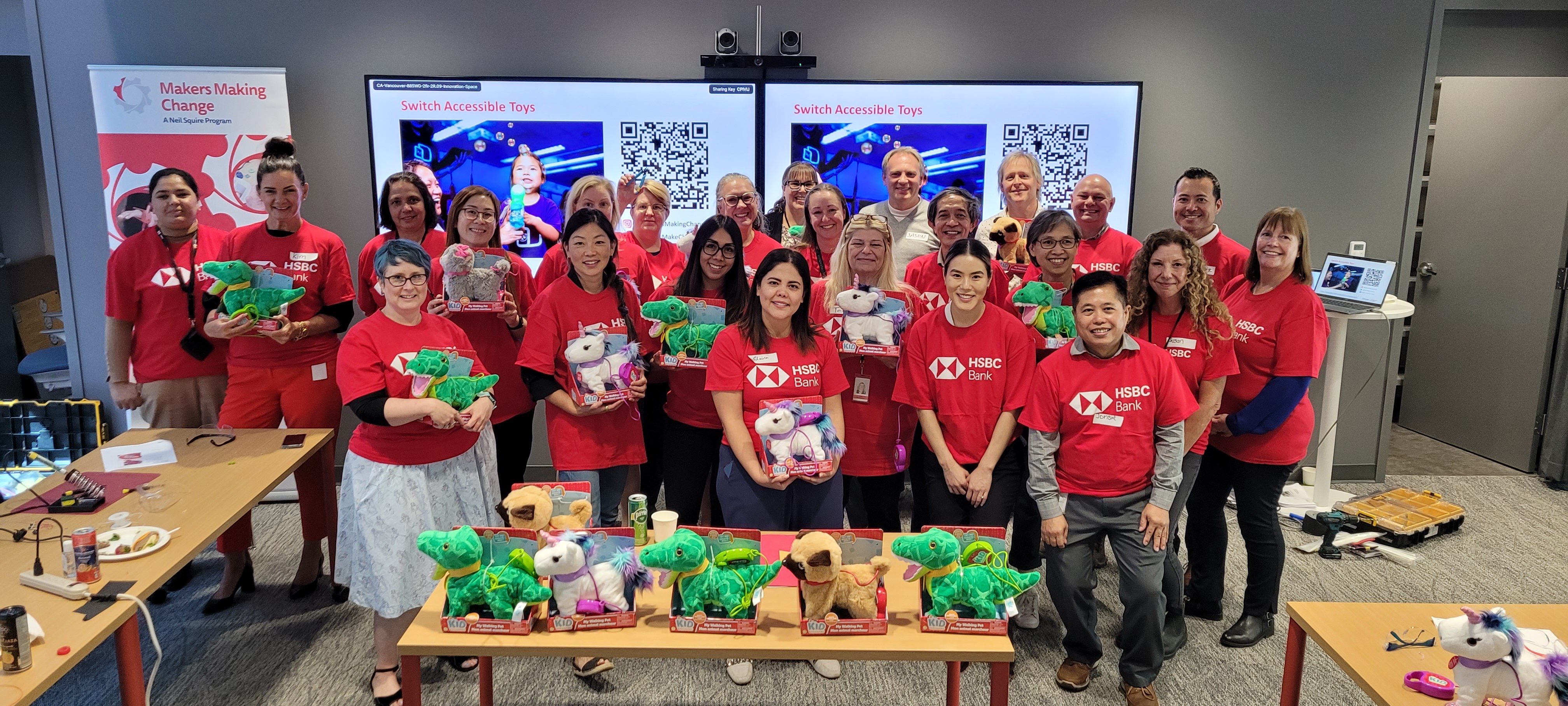 A group of HSBC volunteers in red shirts in front of adapted toys.