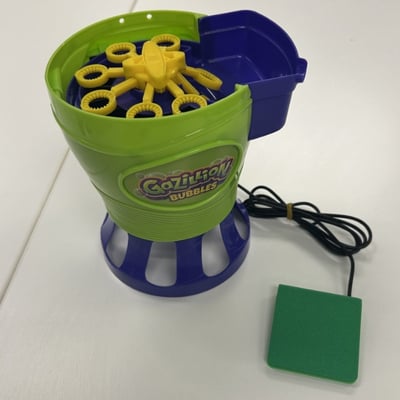 A low profile switch plugged into a large, circular bubble machine with bubble wands on the top
