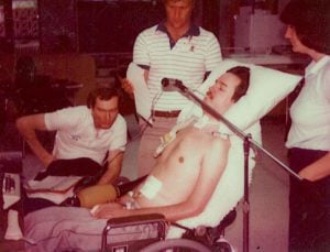 A group of people working with a man in a wheelchair who has a device rigger near his mouth