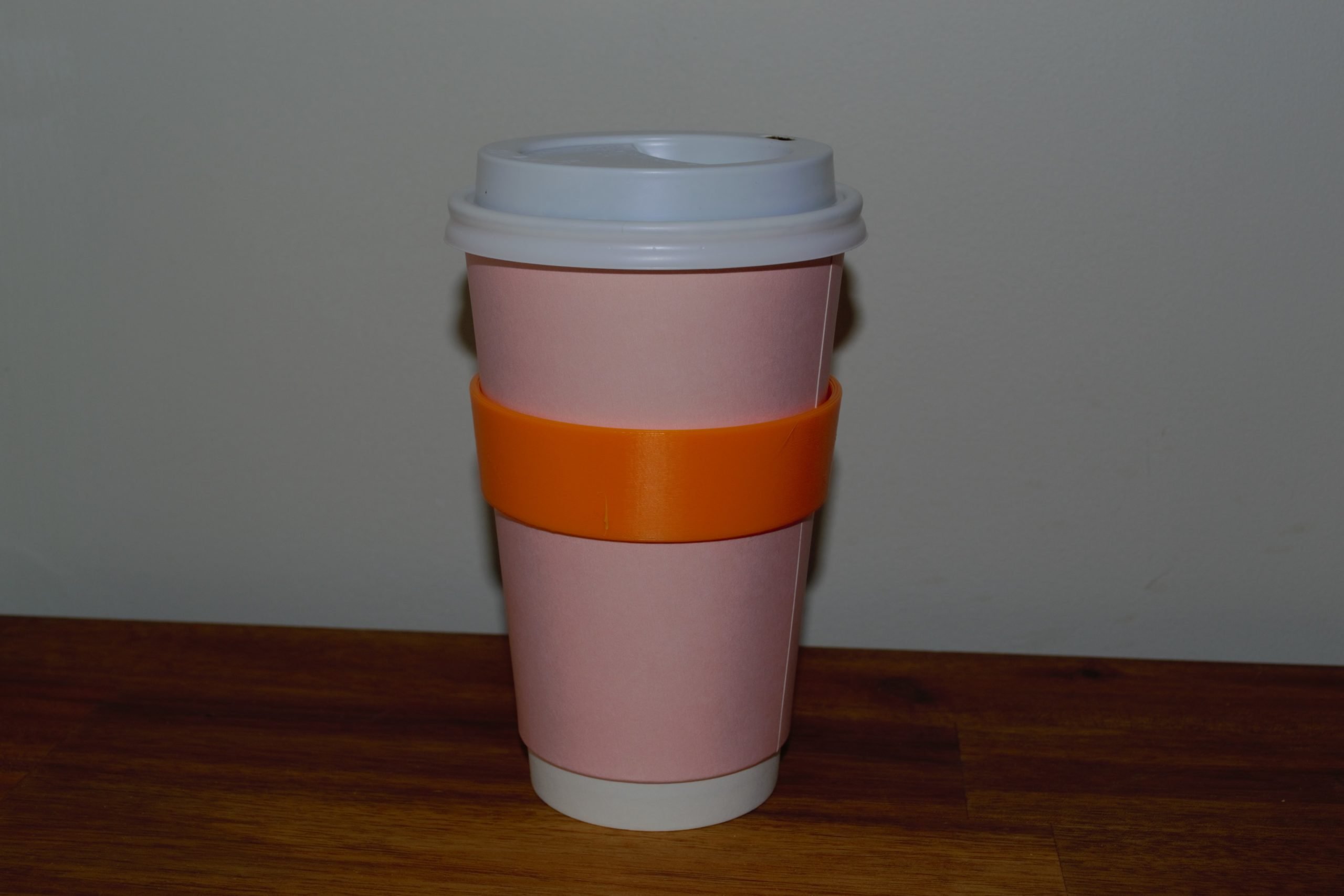An orange 3d printed ring around a disposable cup