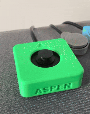 Moving gif of a finger reaching in, moving the Aspen Joystick in a circle, and then the finger goes out of frame. The Aspen Joystick is green, 3D printed, and says "ASPEN" on the front.