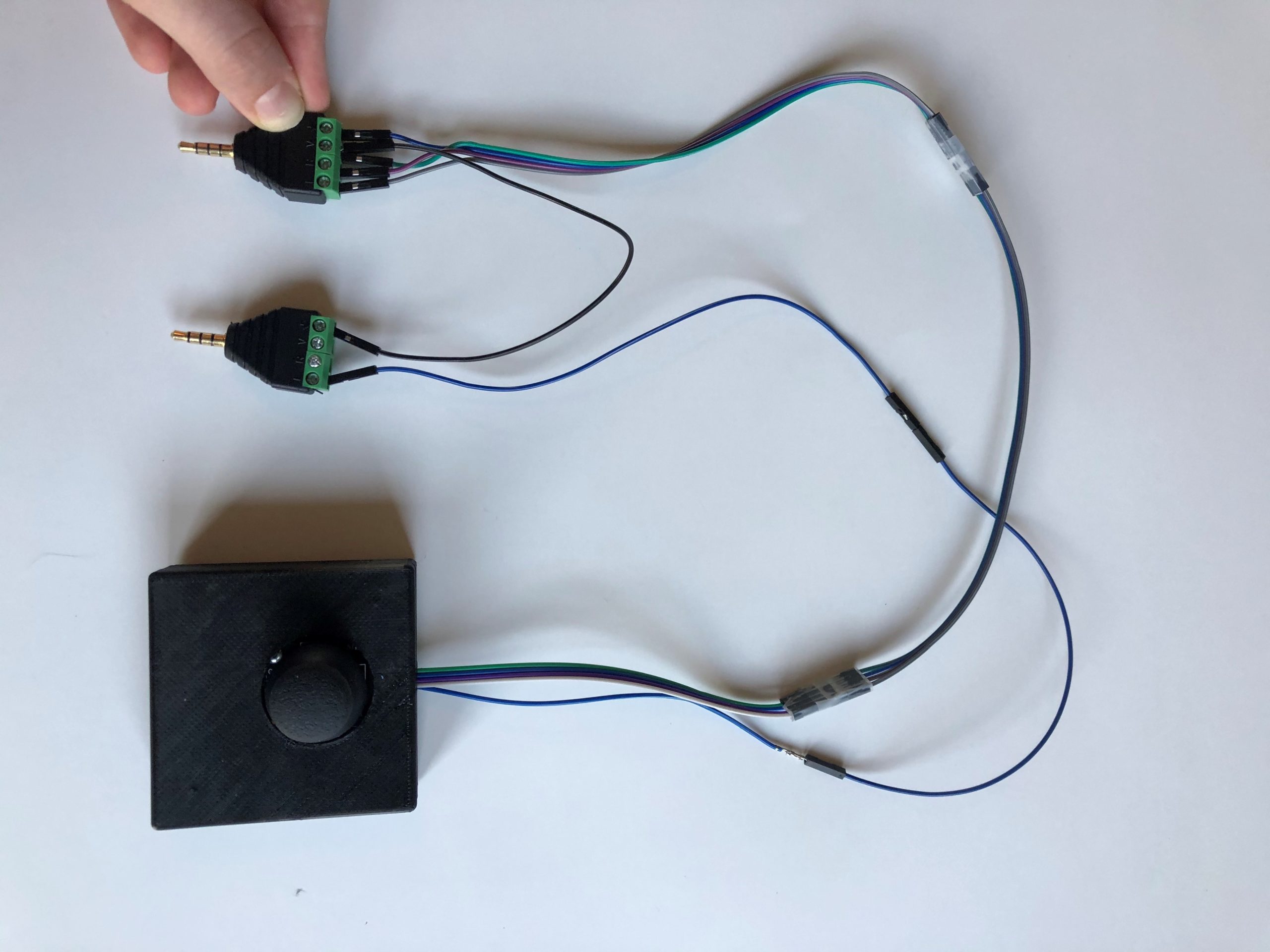 A black 3d printed analog thumbstick with two mono jacks.