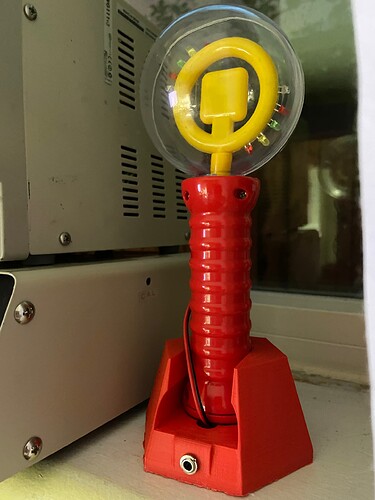 A red and yellow spinning light wand on a red 3d printed base.