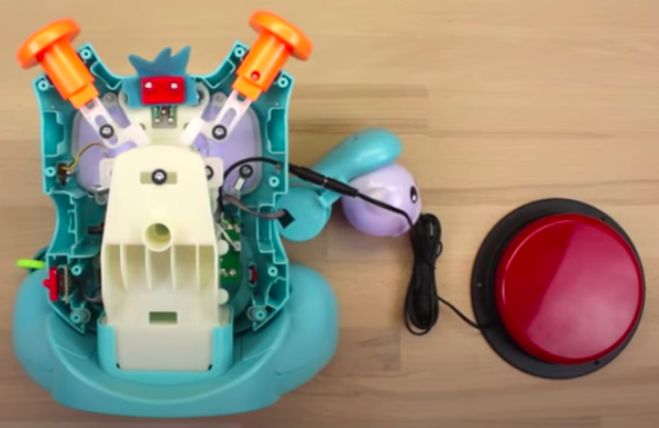 An uncovered Fisher Price Rockit toy with an assistive switch