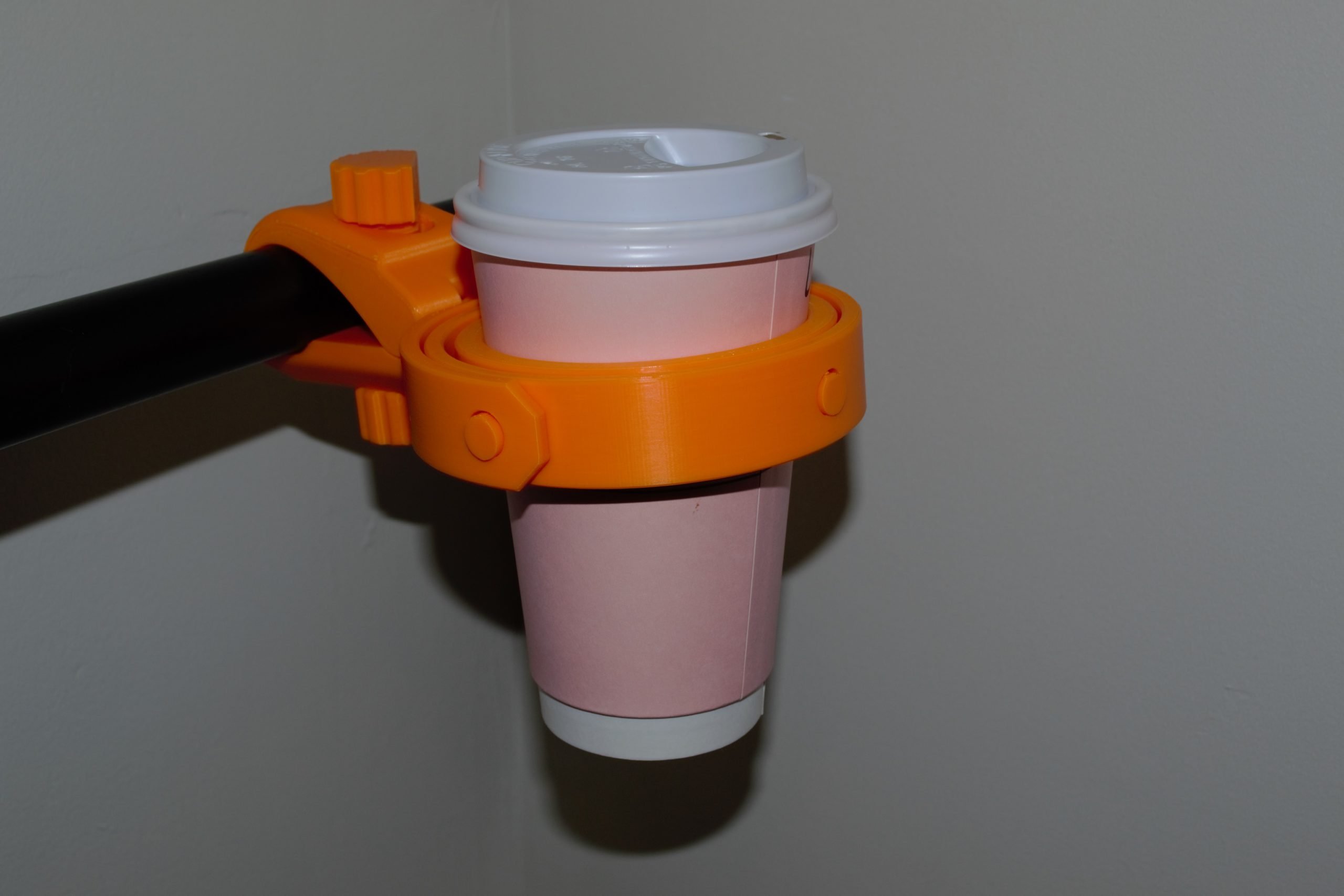 Universal Travel Coffee Gimbal clamped to a round bar holding a disposable coffee cup with the Small Cup Adapter.