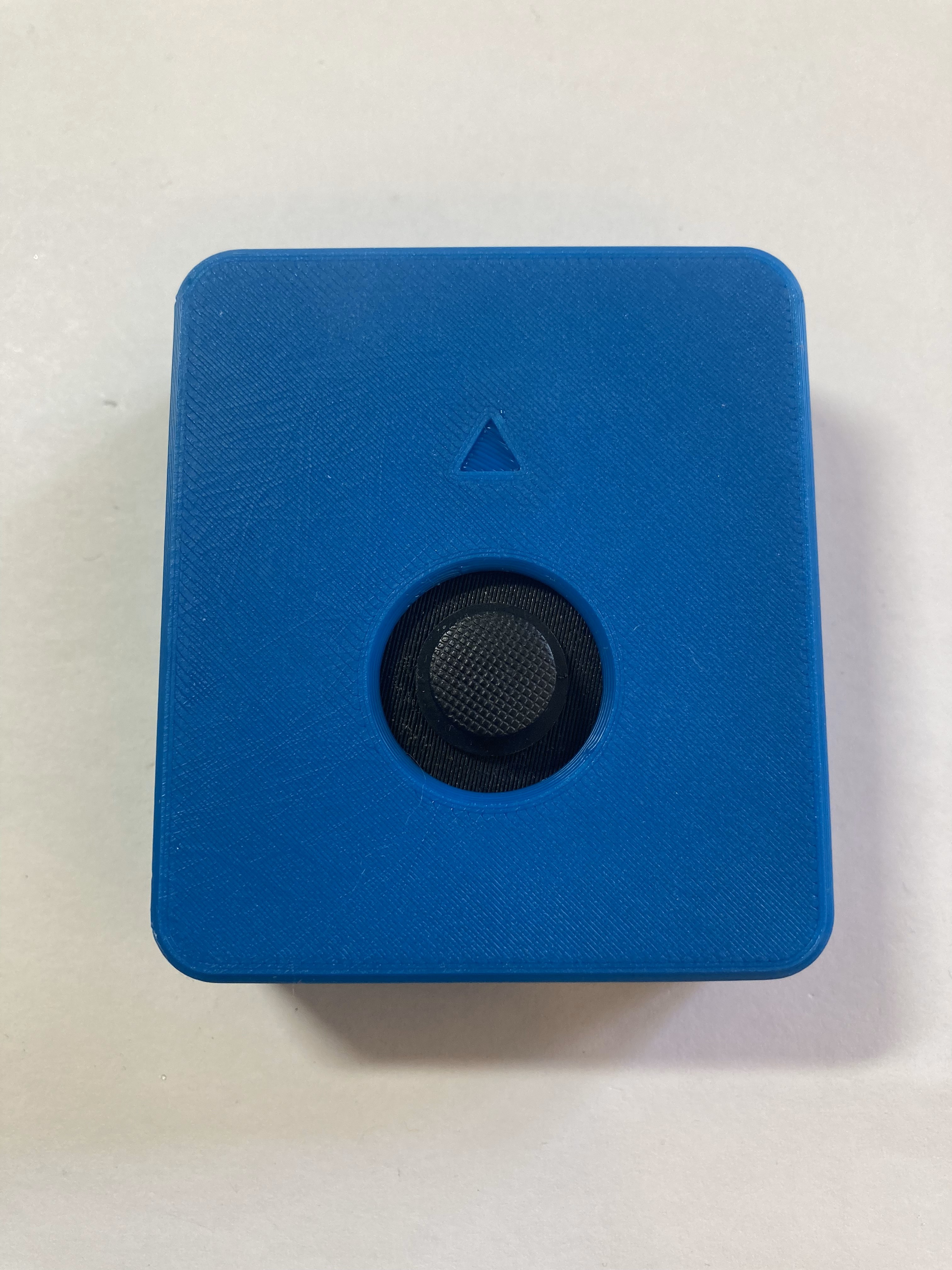 Light blue Birch Sliding USB Joystick on a white background. It is a rectangular shape with a black circle on top, and a smaller elevated black circle that is the joystick topper. There is a small arrow pointing up.