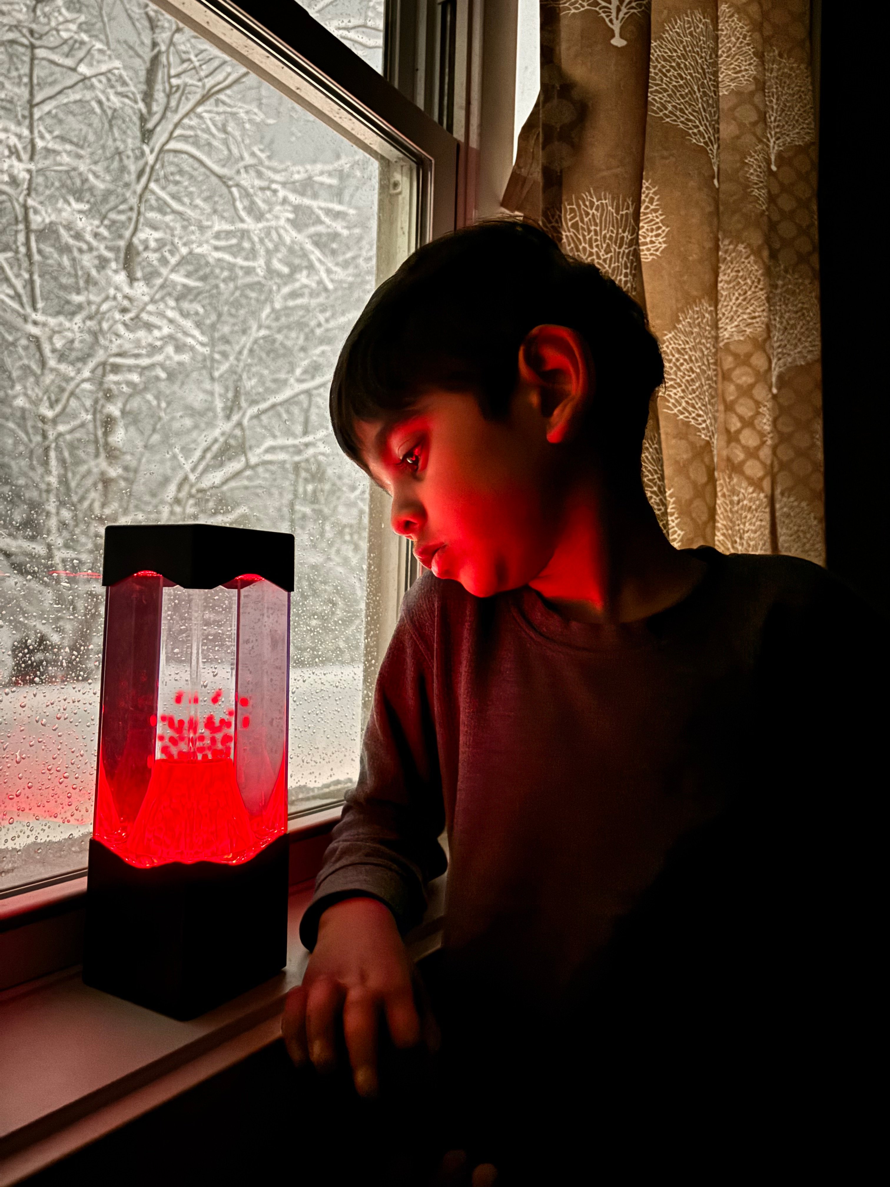 A boy watches his red switch adapted Volcano Lamp toy.