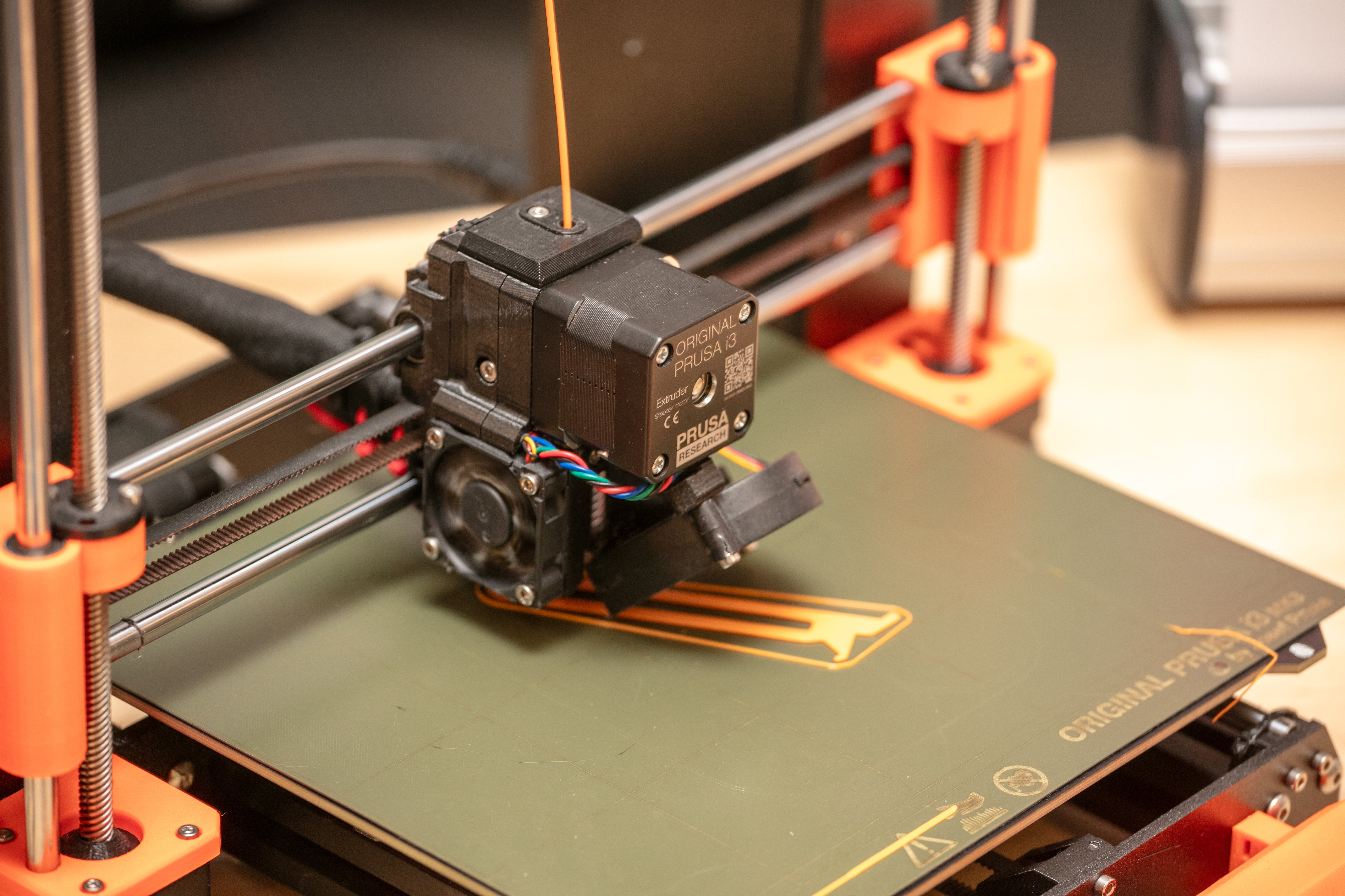 Closeup of a 3D printer head and a print bed