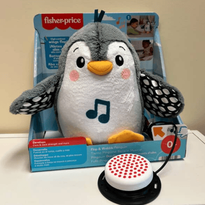 Penguin plush toy with a music note logo on the belly and a switch plugged in.