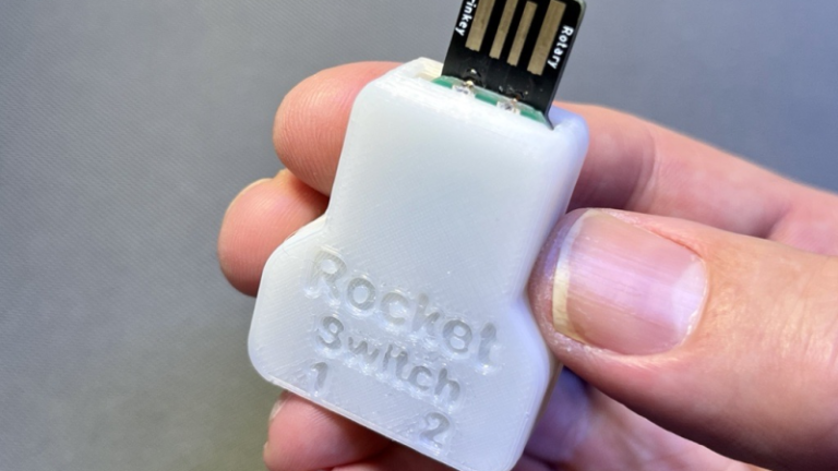 A hand holding a white Rocket Switch.
