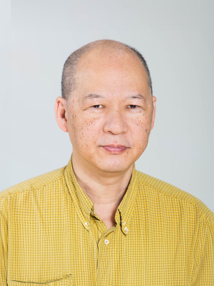 A man with yellow button up shirt against a light grey background.