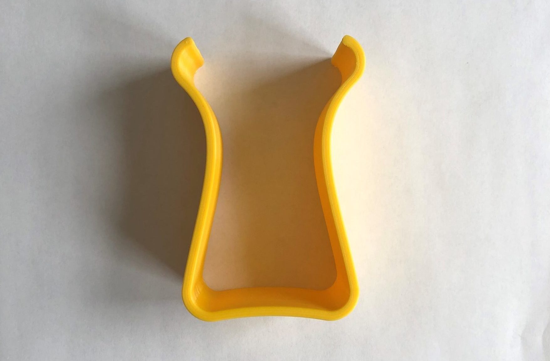 A yellow 3d printed u-shaped magnification stand against a white background.