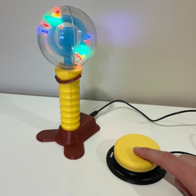 A finger pressing down an interact switch connected to a glowing spinning light wand with a 3D printed base