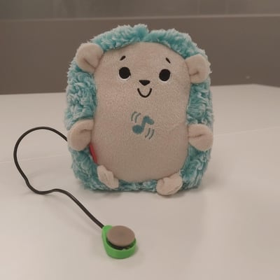 A raindrop switch plugged into a plush toy shaped as a hedgehog