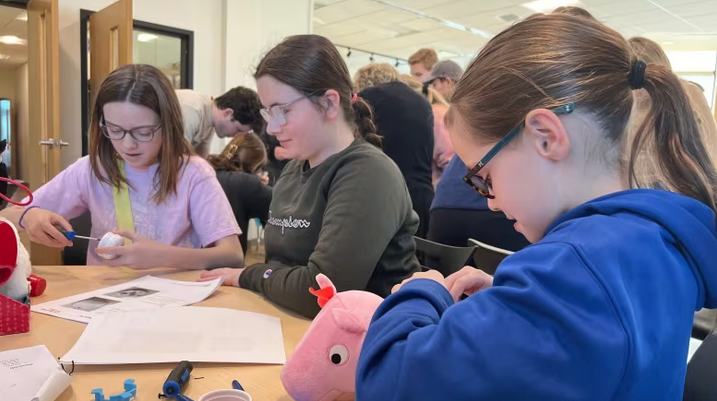 Three young girls adapting a peppa pig toy.