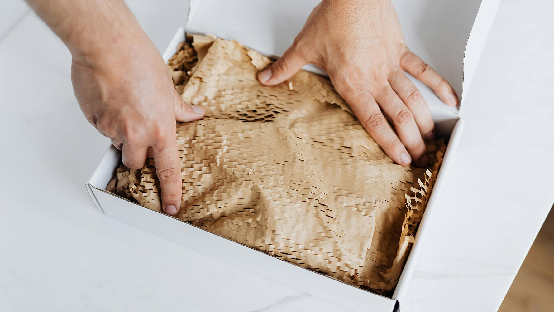 A pair of hands packaging up a cardboard box.