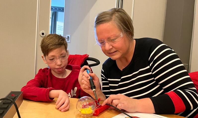 A mom and a young boy soldering together