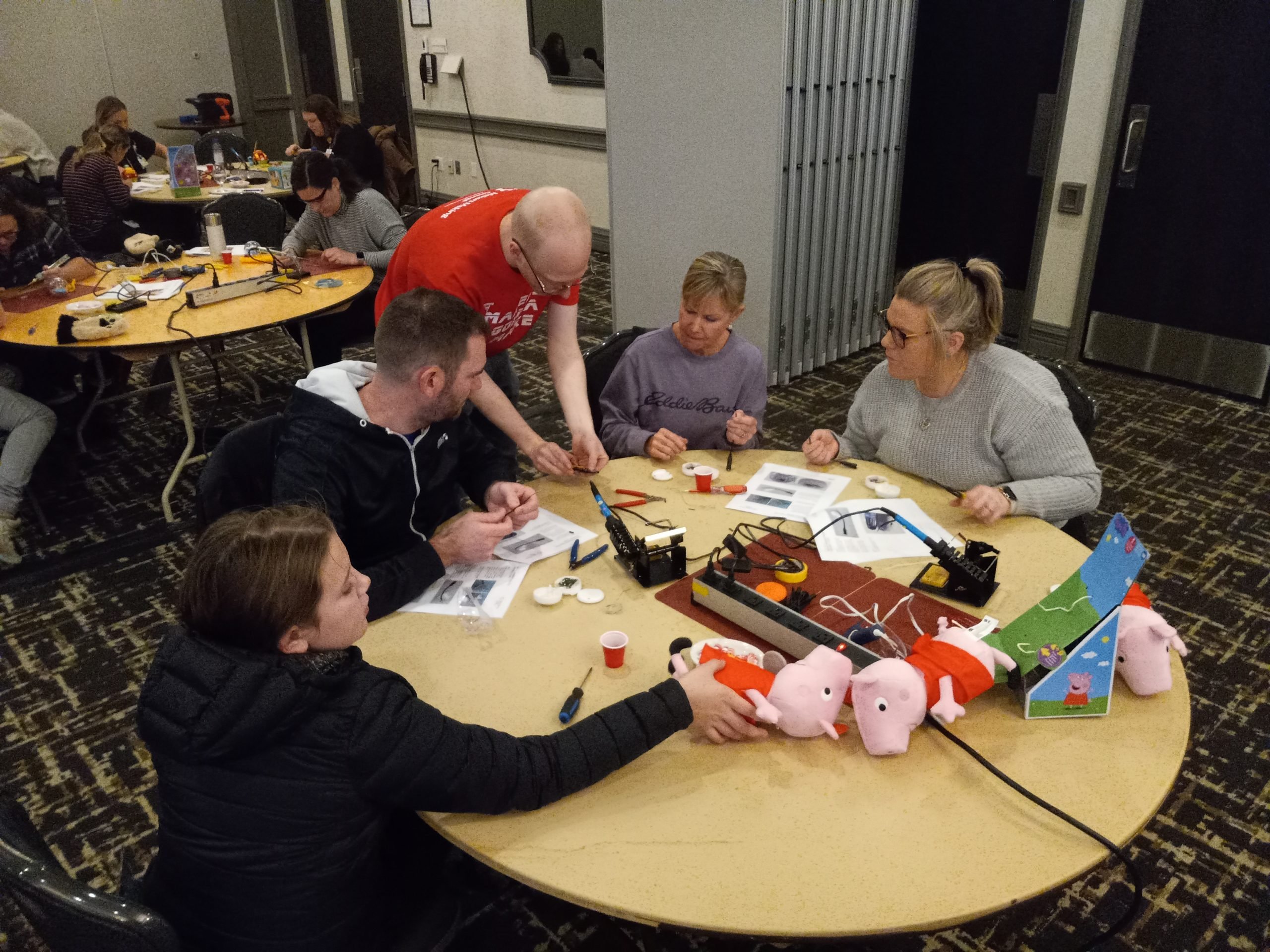 A table of four volunteers watching a Makers Making Change staff demo an adaption.