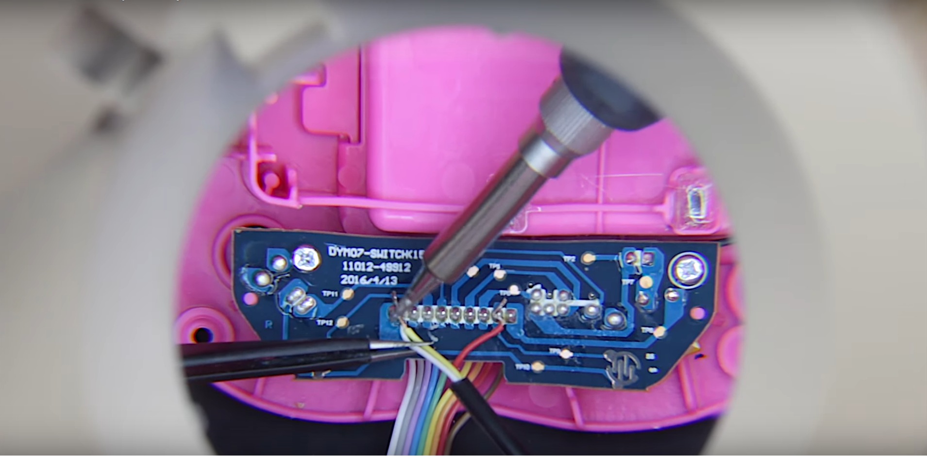 A pink toy opened up so you can see the interior electronics. A soldering iron is being used to make an electrical connection