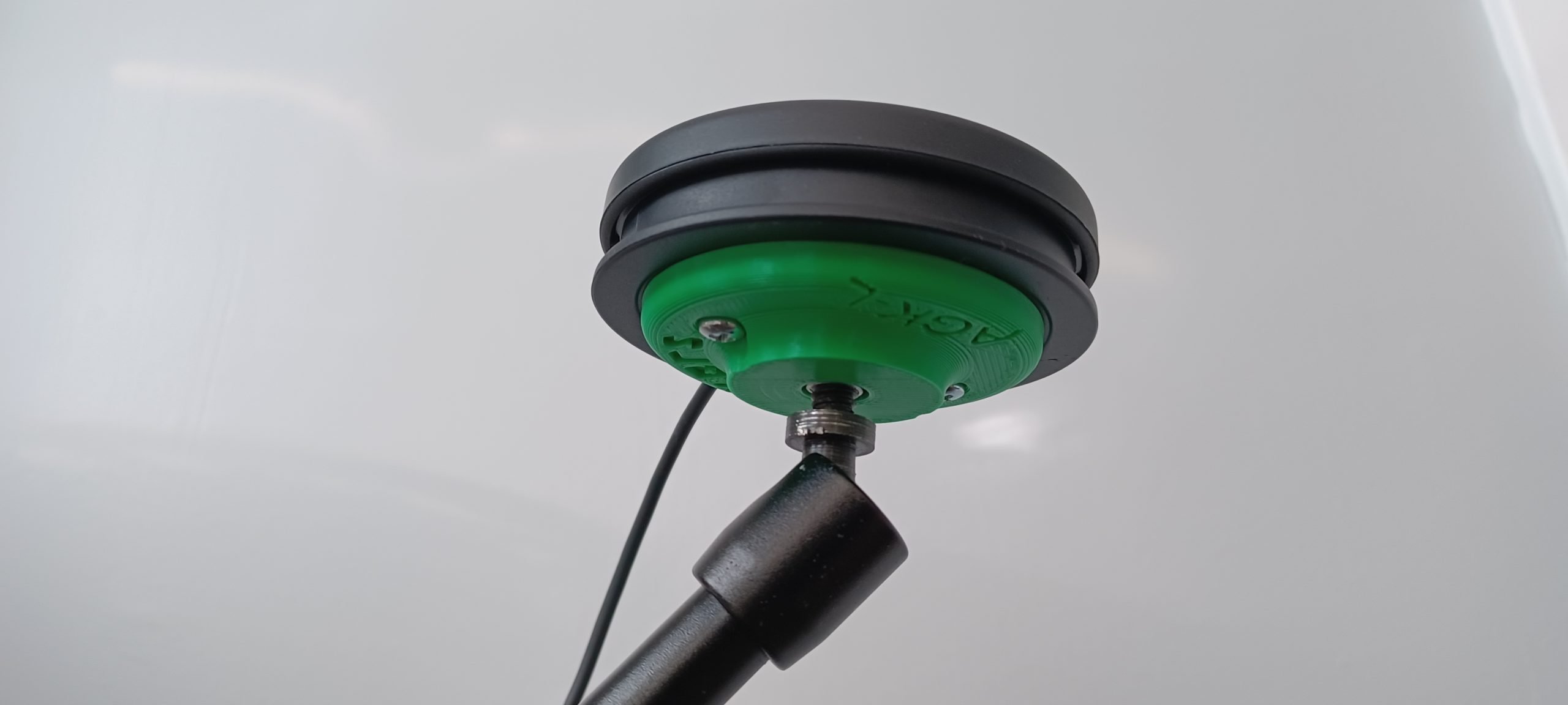A green 3d printed mounting base attached to a black Logitech large button.