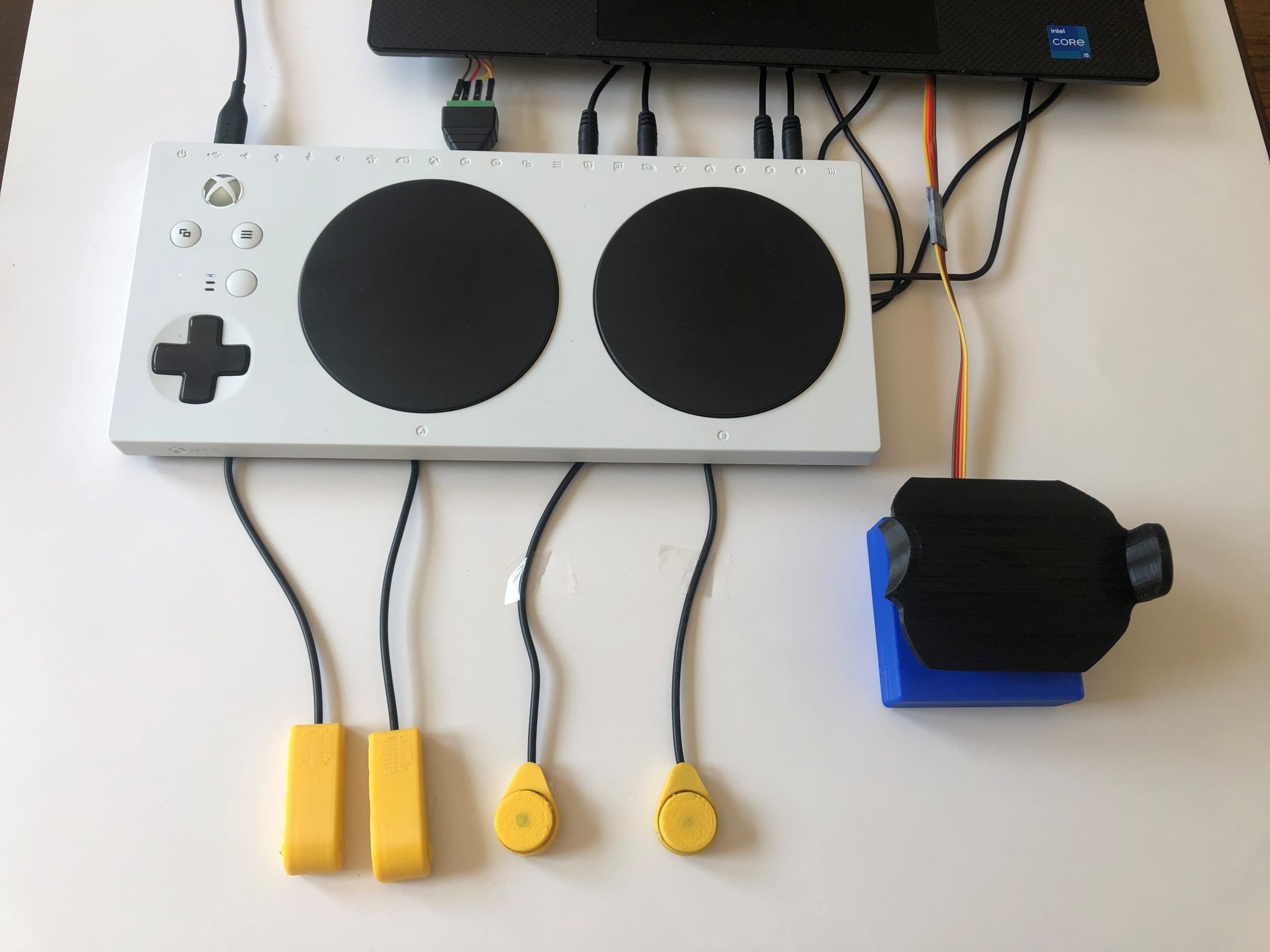A blue and black 3d printed joystick and 4 yellow assistive switches plugged into the Xbox Adaptive Controller.