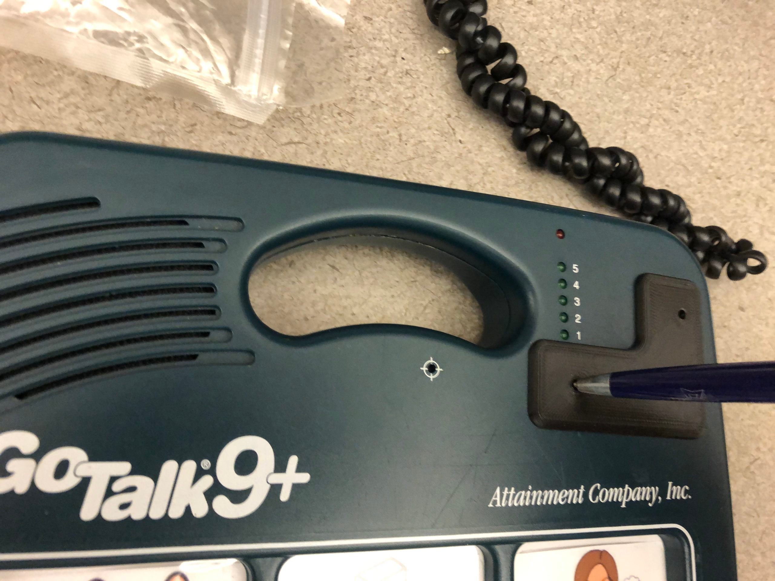 Photo of the Go Talk 9+ with an 3D printed button guard. A pen is being used to press the covered button.