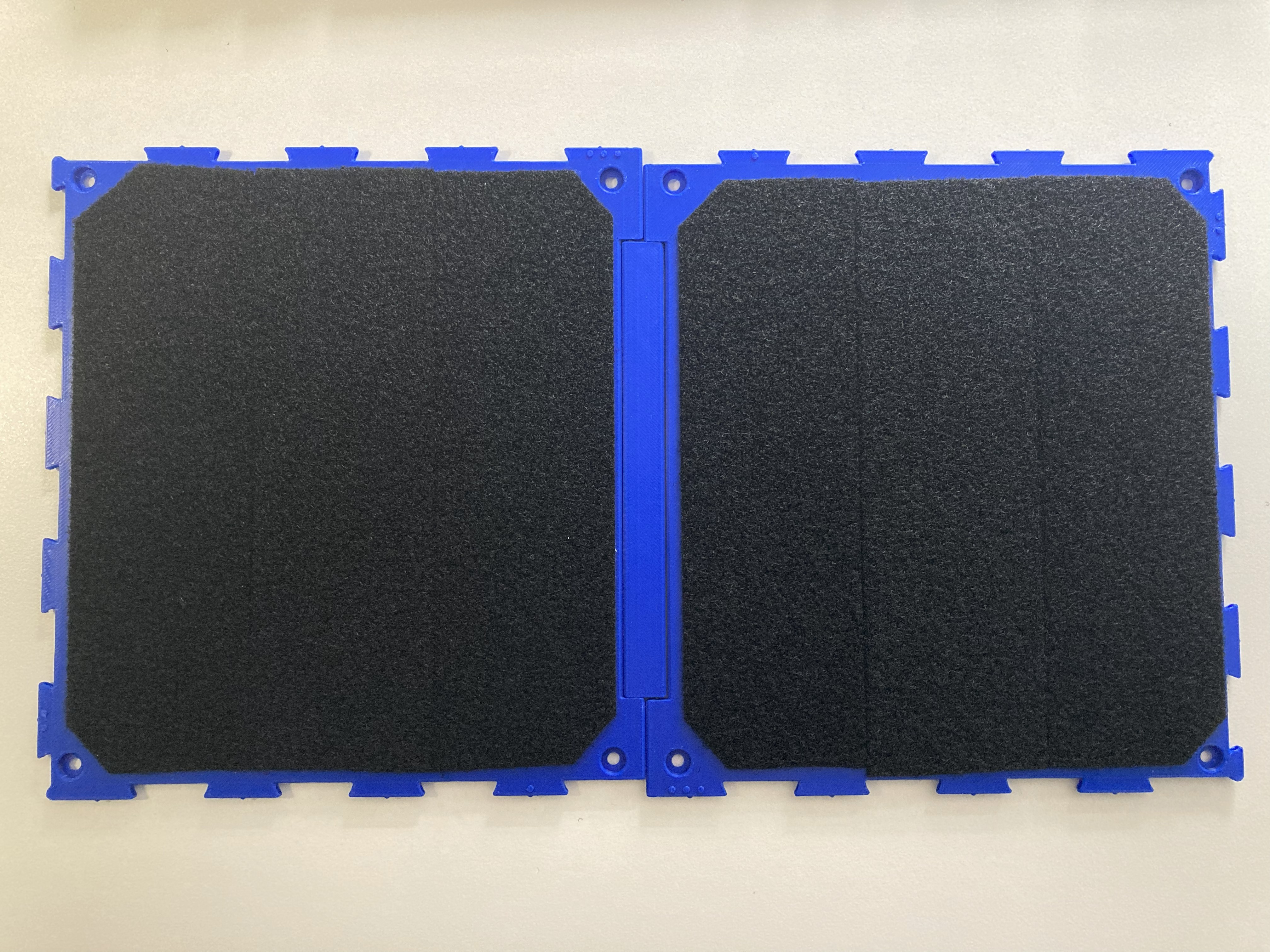 A top down view of the Connect Board Multi, showing the two half plates covered with hook and loop fastener. Interlocking edges around the perimeter of the board provide a way to connect additional boards.