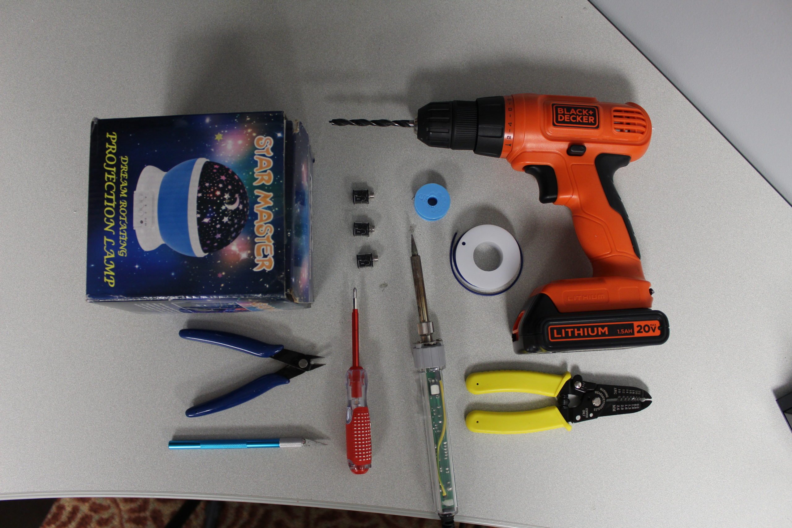 Various hand tools, a soldering iron, and electronic components laid out neatly on a white table.