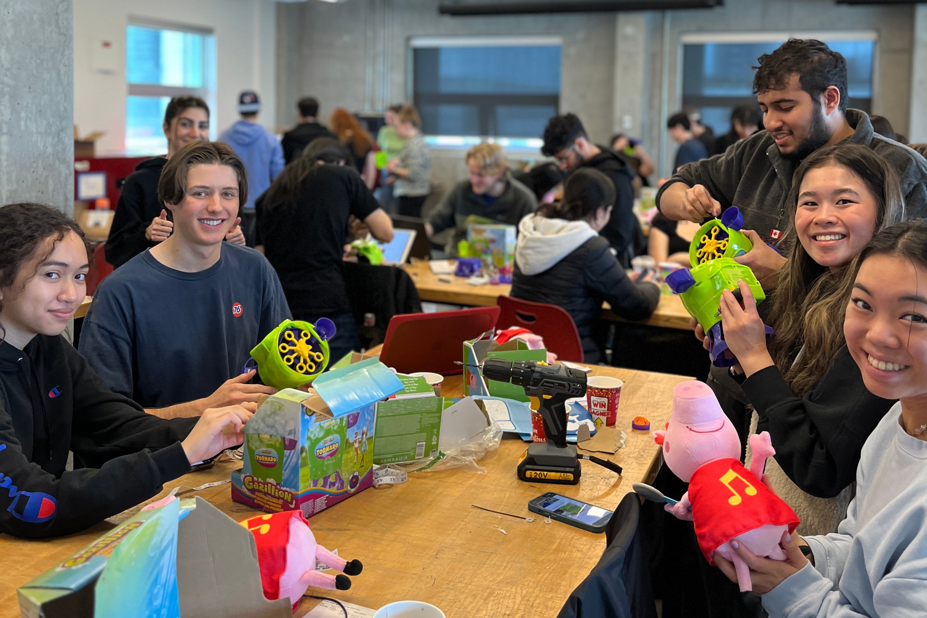 A group of university students at a table adapting a toy.