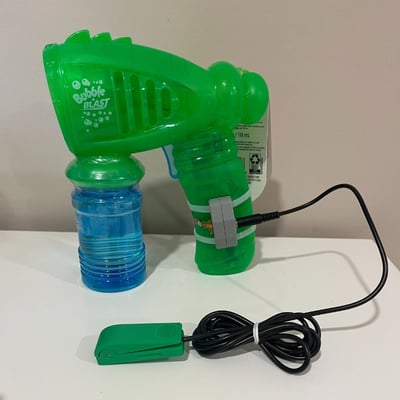 A bubble blaster toy with a 3D printed jack holder connected to the base of the toy with cable ties. A light touch switch is plugged into the jack.