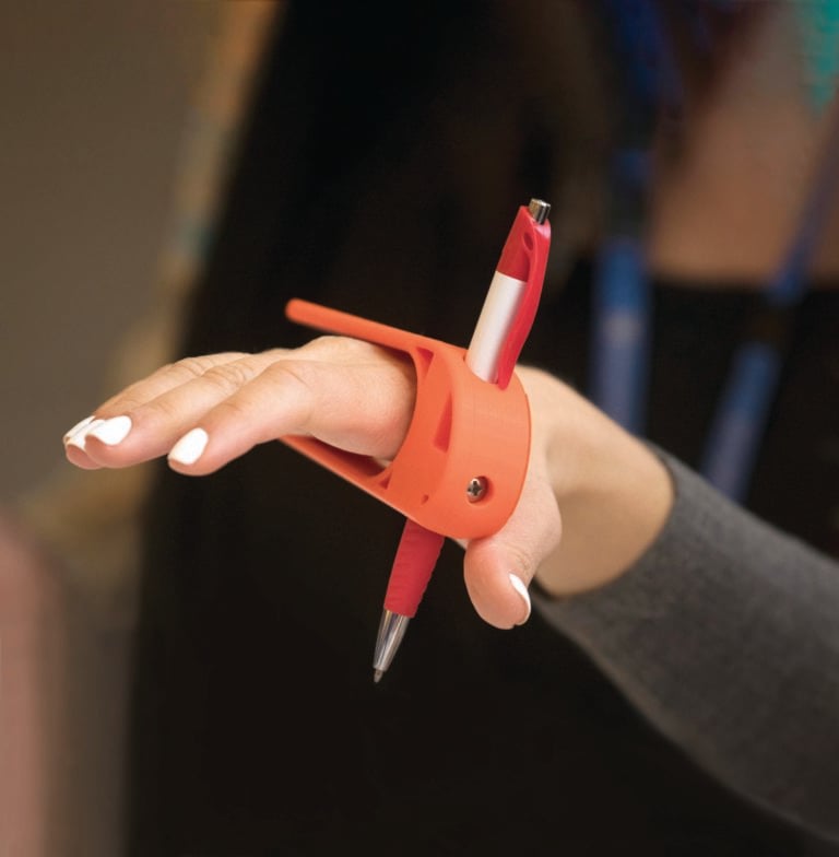 A hand using a red Palm Pen Holder.