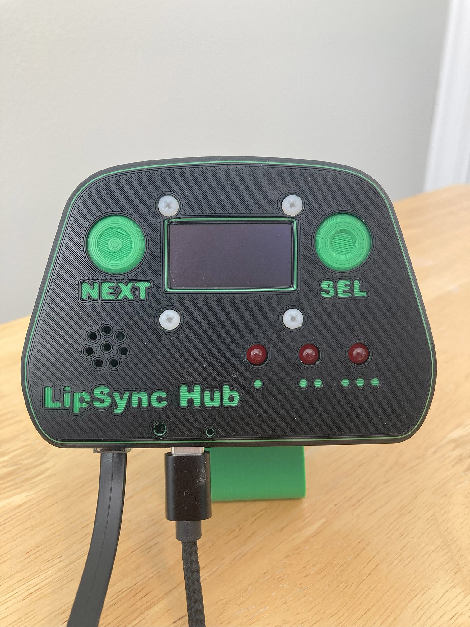 A green and black 3D printed LipSync hub on a stand