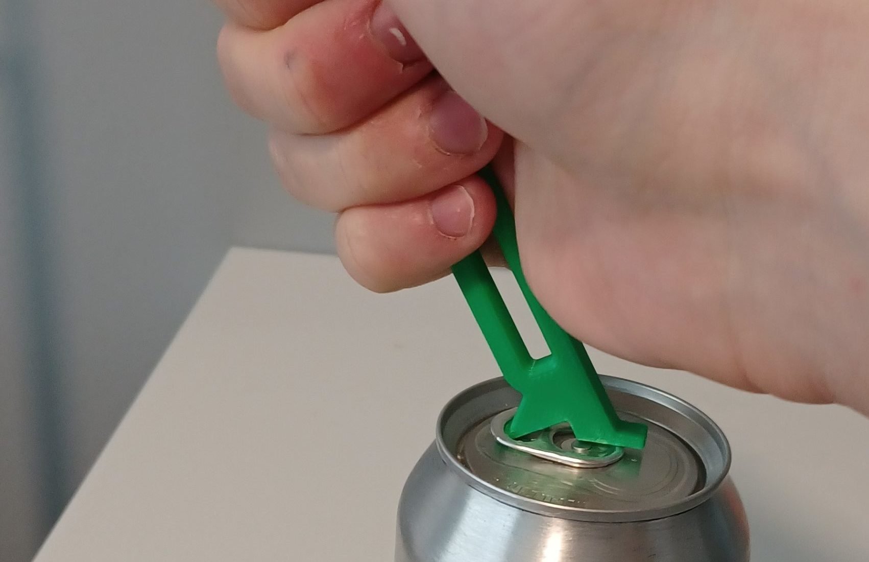 Beverage Can Opener with arrow showing that the can opener must be levered backwards towards the opening of the can.
