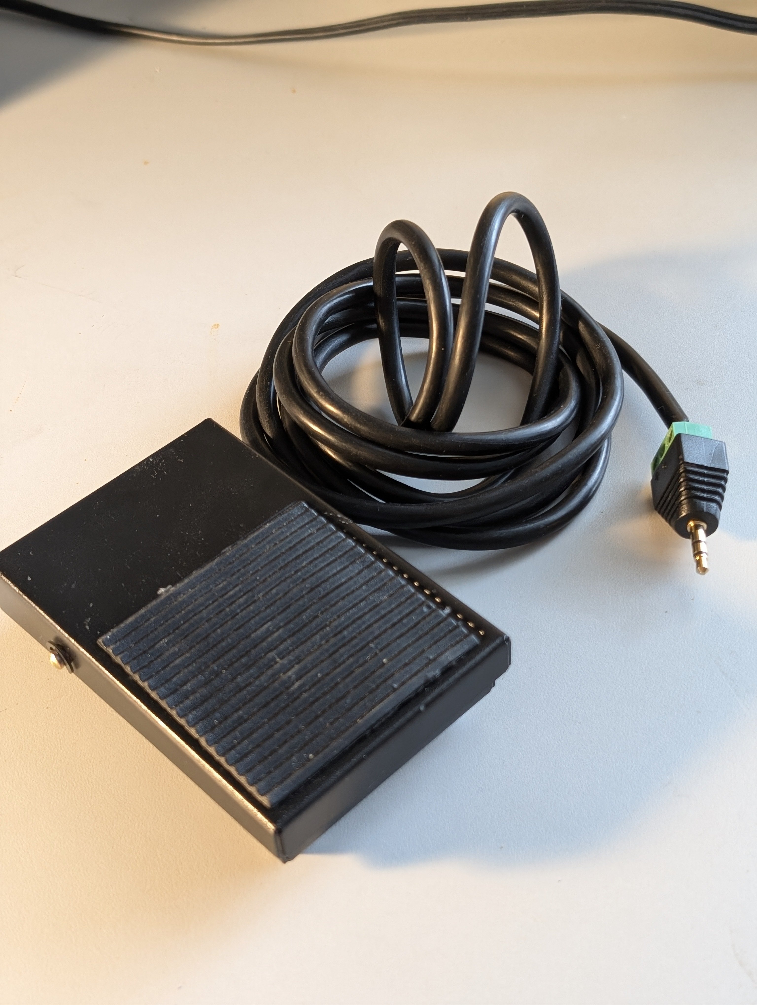 A metal foot pedal switch that has an added 3.5&nbsp;mm plug to function as an assistive switch