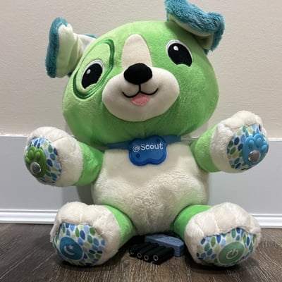 A plush toy shaped as a dog with a collar that says scout and a 3D printed cable clamp containing four mono cables