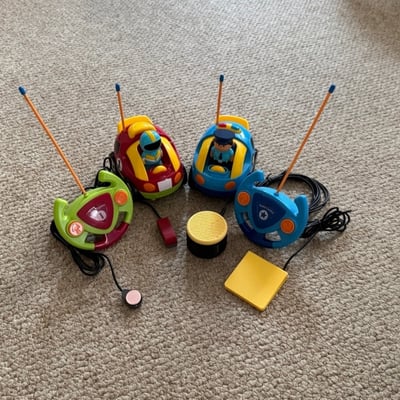 Two sets of remote control cars with their controllers that have two switches plugged in