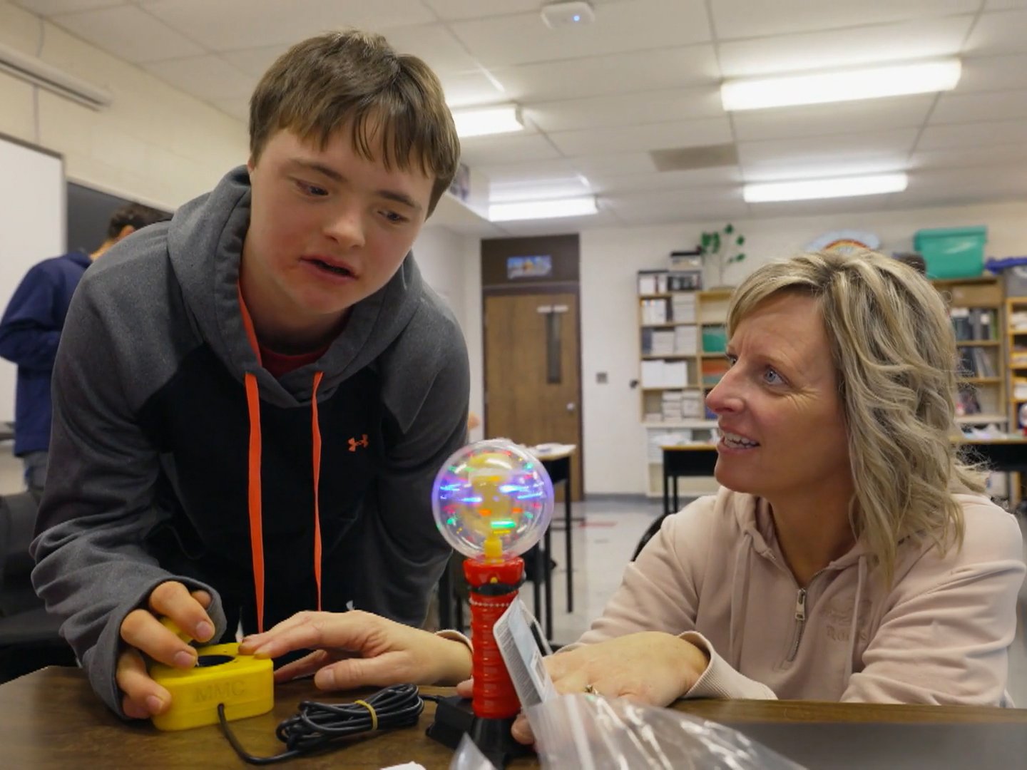 An occupational therapist with a boy playing with an adapted toy