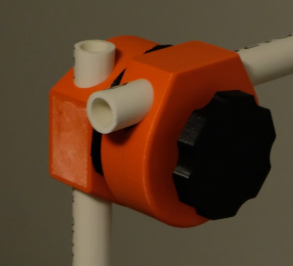 A red 3D printed lockable joint with PVC pipping against a grey background.